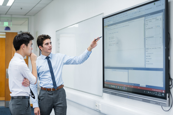 students talking in front of interactive whiteboard